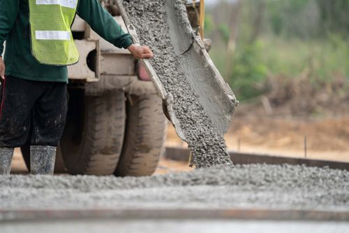 workers pouring ready mix concrete on driveway